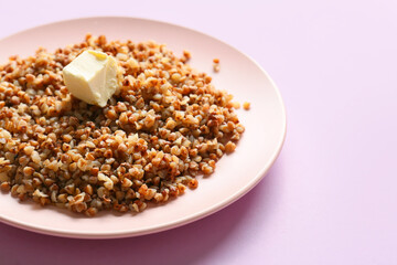 Plate of tasty buckwheat porridge on pink background, closeup