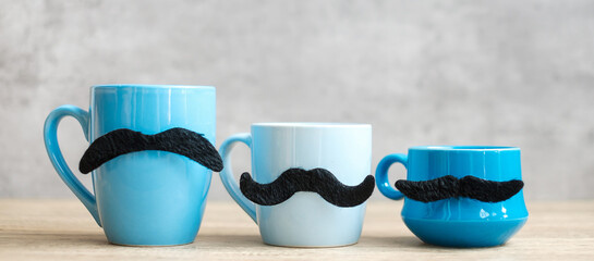Blue coffee cup and tea mug with Black mustache decor on wood table background in the morning. Blue...