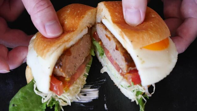 ハンバーガーを半分にする動画。パティとトマトとキャベツを挟んだハンバーガー。