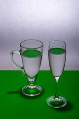 Still life with two glasses of clear liquid on a green table