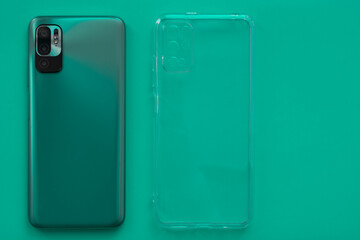 A new smartphone and a silicone case for it lie on a blue, green, turquoise background