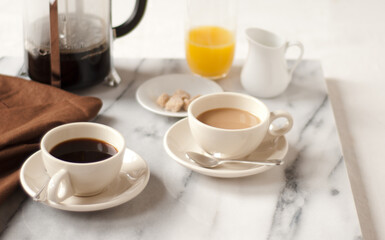 Two Cups of Coffee with a French Press and Orange Juice.