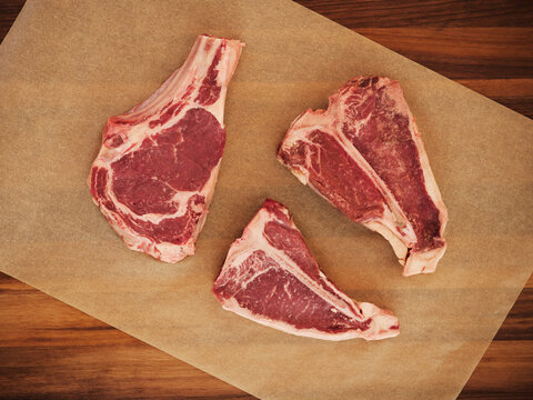 Three Raw Steaks on Parchment Paper.