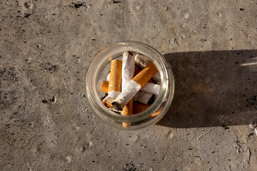Cigarette butts in a glass jar. Smoking concept.