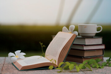 stack of books and coffee mugs and white flowers in summer