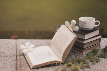 stack of books and coffee mugs and white flowers in summer