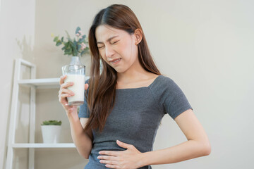 Pain, Allergy asian young woman, girl hand in belly suffer after drink glass of milk, unhappy and bad stomach ache. Lactose intolerance and dairy food , health problem concept.