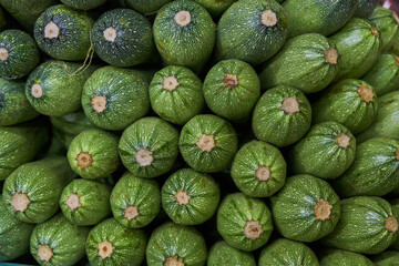 Stacked zucchini on a shelf for sale within a market