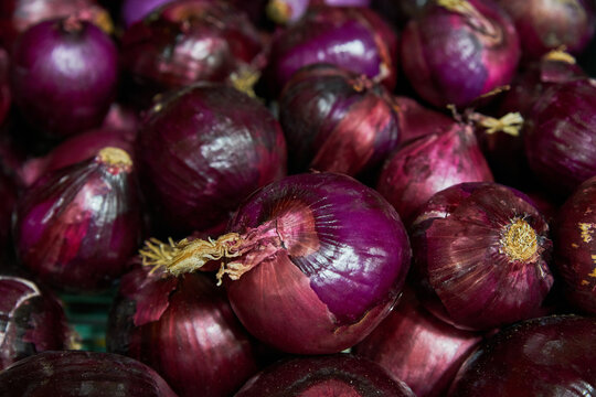 Purple onions placed on a shelf for sale inside a market