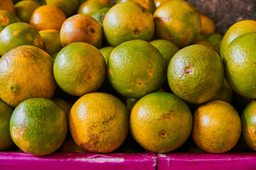 Yellow oranges placed on a shelf for sale within a market