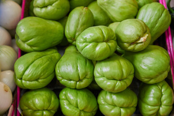 Green chayotes placed on a shelf for sale inside a market