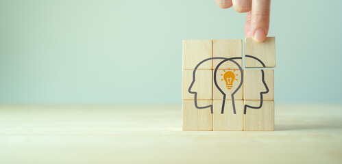 Knowledge and ideas sharing between two people head icon on wooden cube. Transferring knowledge,...