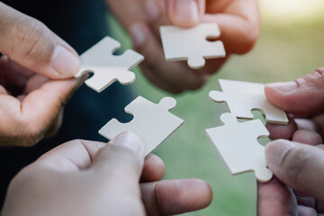 Support, teamwork concept. Close up hands of four businesspeople hold pieces of white puzzle,...