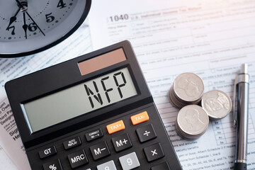 A calculator with the inscription NFP. NFP (Non-farm Payrolls) - acronym on wooden cubes on the...