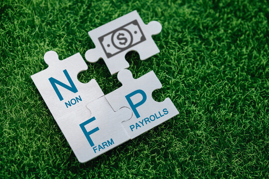 Nonfarm Payrolls - key economic indicator. Natural Family Planning concept. Nonfarm Payrolls on jigsaw puzzles on a green artificial grass background.