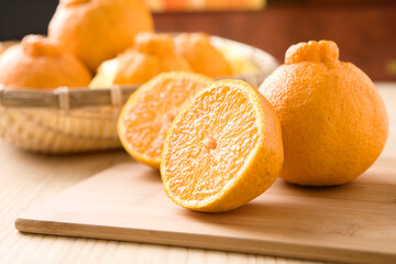 Fresh mandarin oranges fruit or tangerines in a plate on dark wooden table.