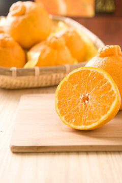 Fresh mandarin oranges fruit or tangerines in a plate on dark wooden table.