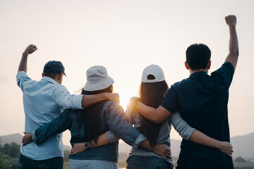 group of people with raised arms looking at sunrise on the mountain background. Happiness, success,...