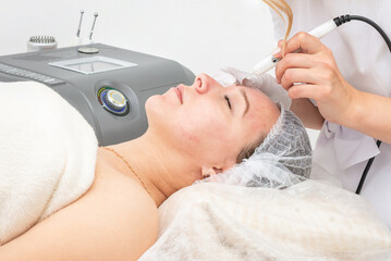 girl at the appointment with a beautician, doing ultrasonic cleaning of the face. Ultrasonic cleaning is a hardware cleaning, which is carried out using high frequency ultrasonic waves.