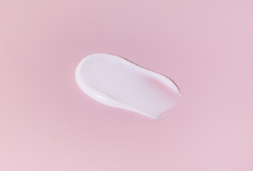 smear of white cream on a pastel pink background