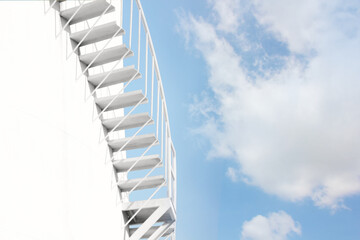 closeup stairs of raw material tank with blue sky white cloud.  White stock bins contain raw materials for processing into products