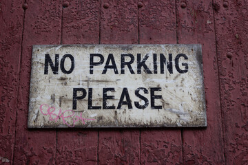 Old No Parking Please sign on wooden door closeup