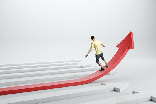 Back view of casual young man balancing on growing red arrow on light background. Improving business and changing direction concept.