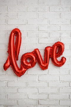 red foil air balloon love letters over white brick wall