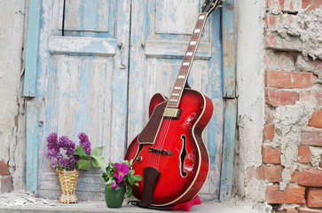 Jazz electric guitar and bouquets of flowers in the window opening.