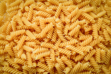 Raw uncooked fusilli pasta, close up background, texture