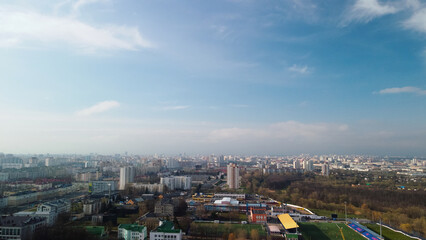 Aerial view of the cityscape. In the backlight of the sun. High-rise buildings on the horizon. In the foreground are one-story houses. Aerial photography.