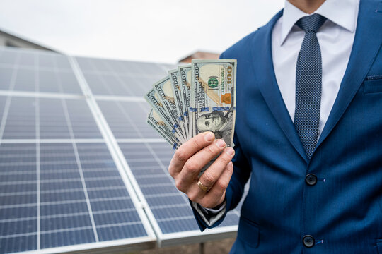 hand of a young man holding dollars for the installation of new solar panels.