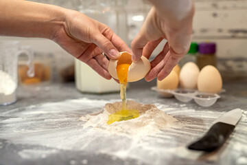 breaking eggs with women's hands into flour to make dough for cakes.