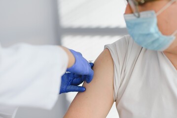 Fototapeta premium Close up of a Doctor making a vaccination in the shoulder of patient, Flu Vaccination Injection on Arm, coronavirus, covid-19 vaccine disease preparing for human clinical trials vaccination shot.