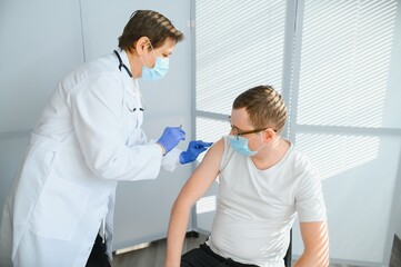 Obraz premium Close up of a Doctor making a vaccination in the shoulder of patient, Flu Vaccination Injection on Arm, coronavirus, covid-19 vaccine disease preparing for human clinical trials vaccination shot.