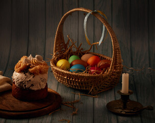 Easter cake, a basket with colored eggs, a bronze candlestick with an extinguished candle, with a...