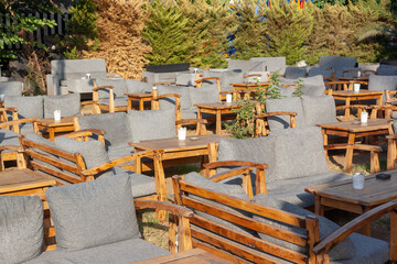 Wooden empty tables and benches with soft gray cushions in cafe.