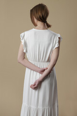 Studio shot of woman in long white summer dress.
