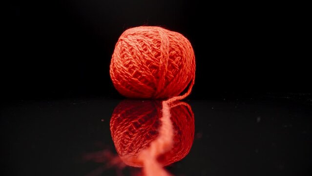A ball of red woolen threads on black glass.. Dolly slider extreme close-up. Laowa Probe