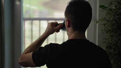 Man silhouette watching through window drink from coffee mug