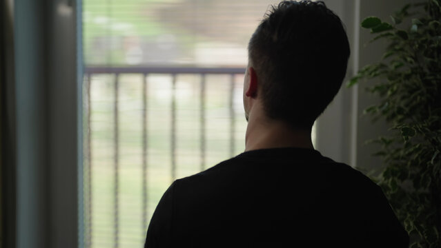 Lonely man silhouette watching through window enjoying view