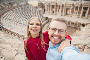 Fototapeta na wymiar Happy lover Couple Tourist taking selfie photo background Amphitheater in Hierapolis ancient city Pamukkale Turkey sunlight