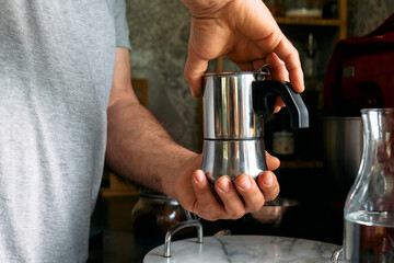 Fototapeta na wymiar Man preparing classic Italian coffee in the mocha in the kitchen. Coffee brake. Morning habit.