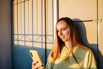 A woman is smiling and looking at phone.