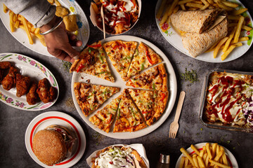 The hand of a guest takes a slice of pizza at the restaurant table
