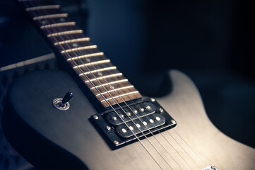 Naklejka premium Close-up, black electric guitar on a dark background.