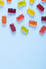 Colored jelly bears on a pastel blue background with copy space. Top view