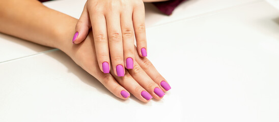 Obraz na płótnie Canvas Beautiful manicure with purple, pink nail polish on young caucasian female hands