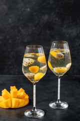 Dessert champagne jelly with exotic fruits - mango and pitahaya in a glass. On a black background