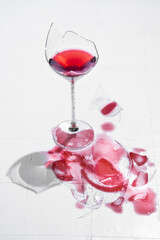 Broken glass with red wine on a table with white tiles